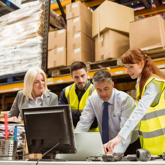 four warehouse workers surround a computer